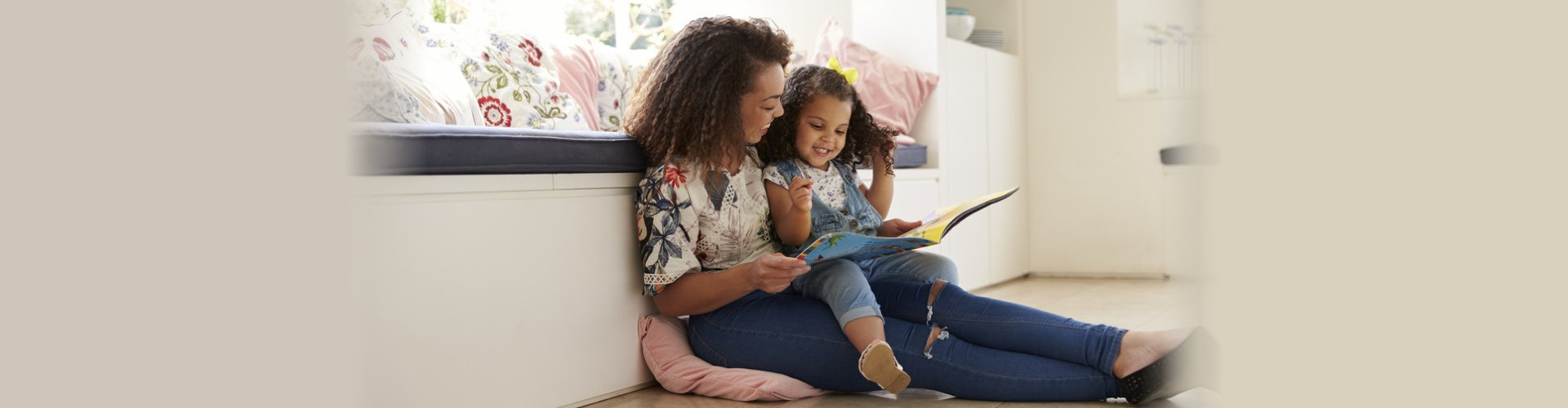 Mother sitting on the floor reading a book with her daughter